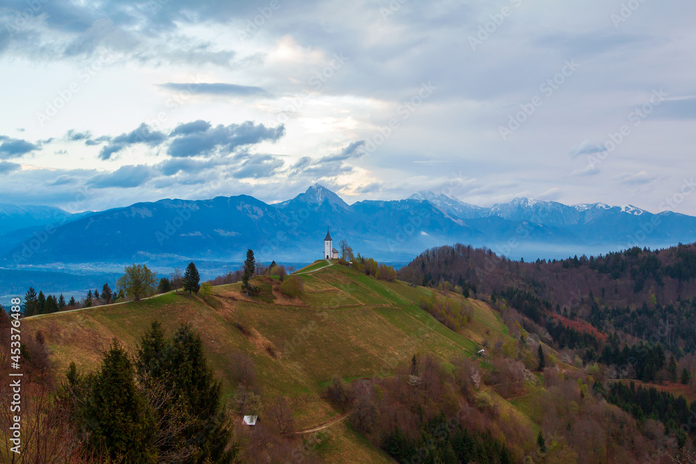 Fototapeta premium On the hilltop the magnificent Church of St. Primus and St. Felician with beautiful views of the landscape, Jamnik village, Kranj village at sunrise, Triglav National Park