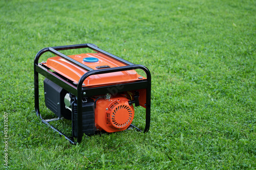 Portable electric generator on the green grass outdoors photo