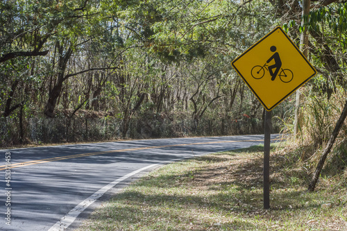 cyclists on the lane written on a sign that is on a road, copy space to the left