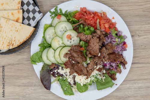 Overhead view of health conscious eaters can have the greek salad loaded withf fresh vegetables and served with pita quarters photo