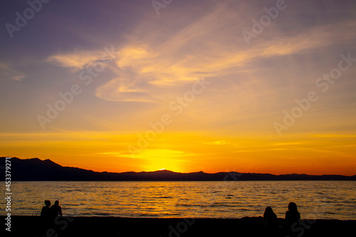 Beautiful sunset over Lake Tahoe CA USA with sihlouttes of two couples on beach watching
