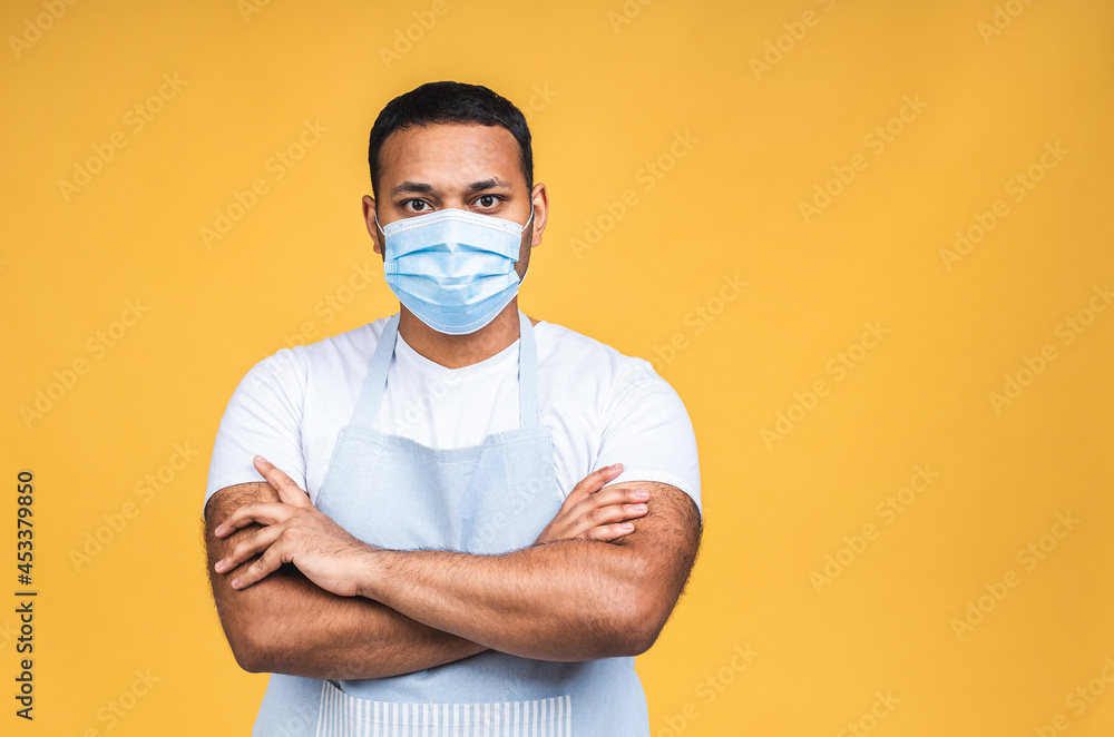 Portrait of african american black indian chef or cook with mask for coronavirus prevention isolated over yellow background whit copy space. Portrait of african american black indian chef or cook with mask for coronavirus prevention isolated over yellow background whit copy space.