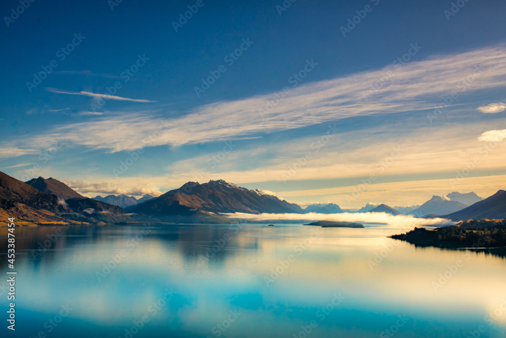 Stunning panoramic view of the Southern Alps  and the mountain reflections on the very calm still water of Lake Wakatipu