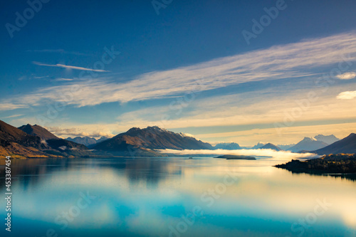 Stunning panoramic view of the Southern Alps  and the mountain reflections on the very calm still water of Lake Wakatipu © Stewart