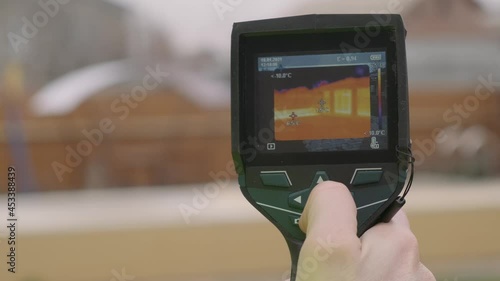Close-up of a builder analyzing heat on a wall with a building thermal imager. Inspection of structures   photo