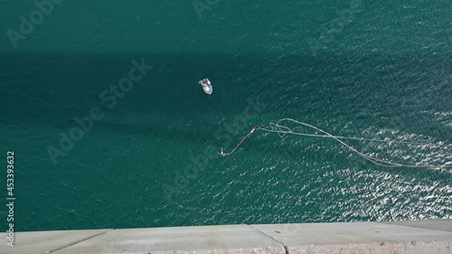 Bungee jumping. Young girl is jumping. Bungee jump from Maslenica bridge above sea. Jump off a bridge with a rope. Girl having a good time bungee jumping. Extreme sport, adrenaline and adventure.	 photo