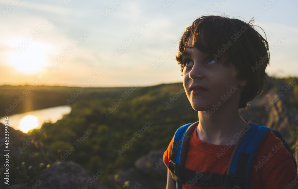 Portrait of a boy with a backpack on the background of the setting sun Portrait of a boy with a backpack on the background of the setting sun