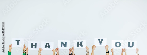 Studio shot of unrecognizable unidentified group of staff officer in corporate office holding thank you alphabet cardboard paper sign over head showing appreciation to customer on white background photo