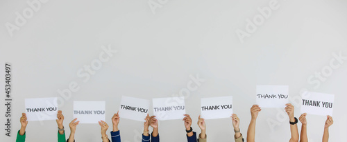Studio shot of variety fonts thank you letters paper sign holden above head by group of unrecognizable unidentified faceless officer staff showing appreciation to customers on white background photo