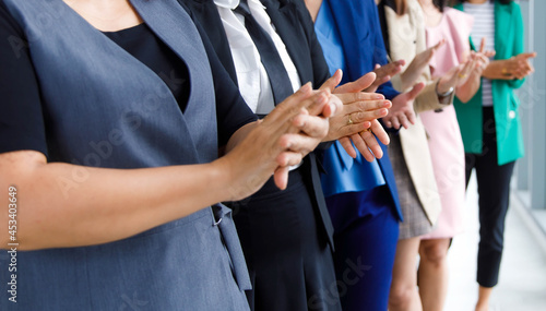 Incognito unidentified unrecognizable faceless group of female office staff in business wears standing ovation side by side clapping hands celebrating for colleague promotion in company meeting room photo