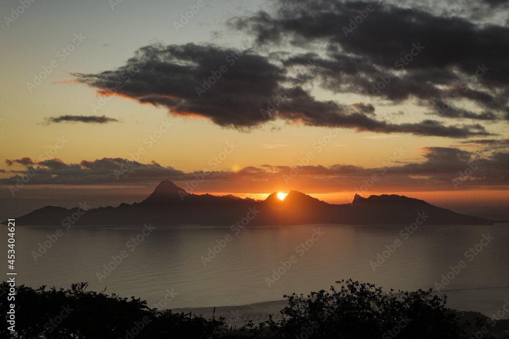 A perfect sunset between two mountains of the island of Moorea in french polynesia