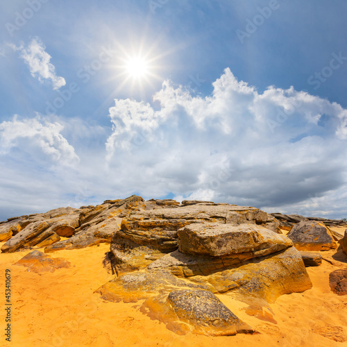 sandy desert with heap of huge stones at sunny day