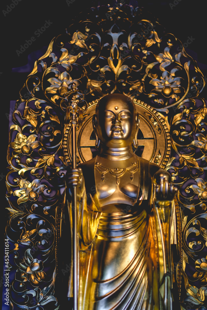 Beautiful details of a golden standing buddha sculpture at a buddhist temple in Kamakura, Japan