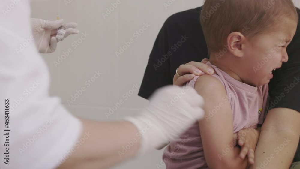 Doctor makes vaccination in the children's hands. Two years old kid crying while he is given an injection of a syringe in the shoulder close-up. 4k Doctor makes vaccination in the children's hands. Two years old kid crying while he is given an injection of a syringe in the shoulder close-up. 4k