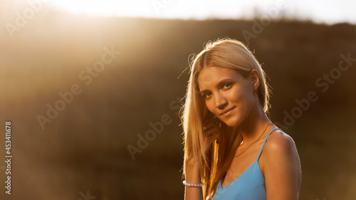 Fotografie Portrait of a young attractive girl in backlight against blurred background