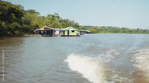 Boat at high speed amazon river with floating houses
