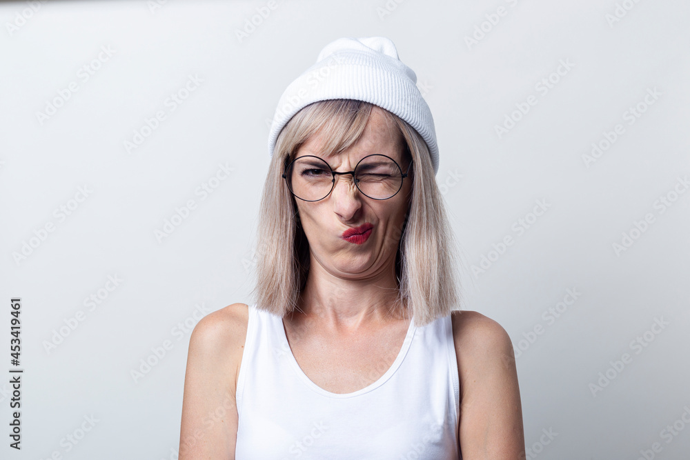 Young woman squinting grimace glasses, a white cap on a light background Young woman squinting grimace glasses, a white cap on a light background