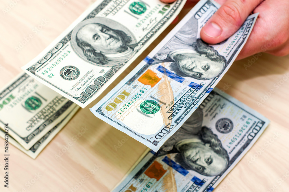 a man puts hundred-dollar bills into two piles on the table a man puts hundred-dollar bills into two piles on the table