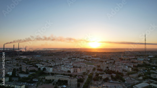 Obraz na płótnie An epic sunset with a view of the smoking factory and the city. The embankment of Lake Balkhash. Low houses are standing and there are few trees. The pipes from the factory are smoking. Kazakhstan w salonie