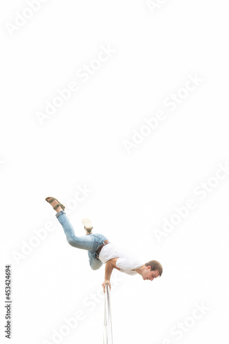 Casual dressed man making calisthenic exercises for joy on an urban handrail. Working out without effort concept. Minimal composition with copy space