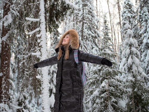 A happy smiling woman with a hood on her head embraces nature around her.