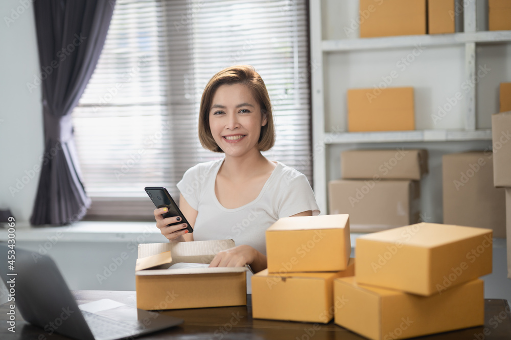 Startup small business entrepreneur SME freelance woman work with smart phone, Young Asian small business owner use computer, online market packing box delivery, SME e-commerce telemarketing concept Startup small business entrepreneur SME freelance woman work with smart phone, Young Asian small business owner use computer, online market packing box delivery, SME e-commerce telemarketing concept