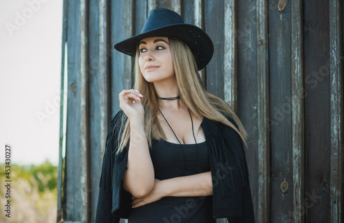 Girl in American country style black boho jacket with a fringe and cowboy hat at nature