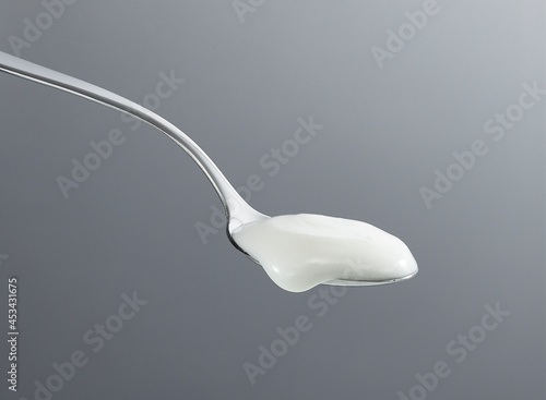 фотографія Spoon scooping yogurt isolated on gray background