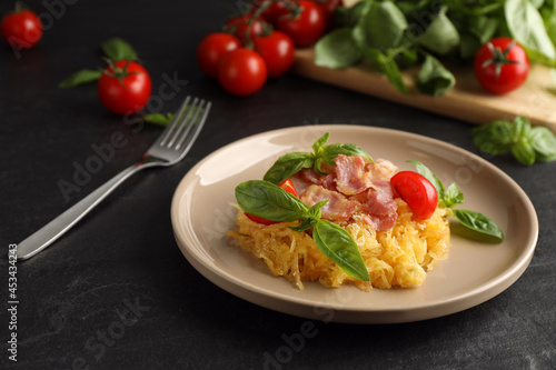 Tasty spaghetti squash with bacon and basil served on black table