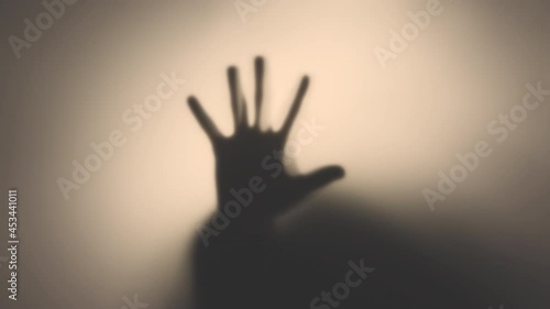 4k video of a silhouette of a man's hand behind a translucent glass. The concept of the other world, victims of violence, paronormal, ghosts. photo