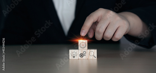 Businessman choosing wooden blocks with business strategy and action plan icons.