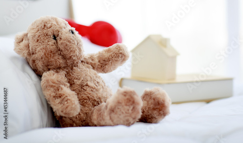 Brown lovely fluffy teddy bear toy sitting alone on bed in bedroom