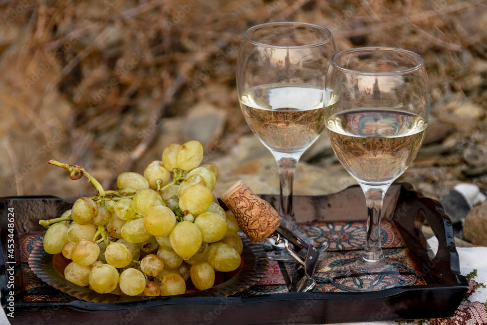 Fototapeta premium Wine glasses and grapes on wooden tray in nature, agricultural, viticultural concept