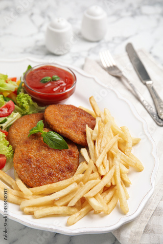Delicious fried breaded cutlets with garnish served on white marble table