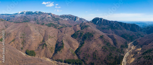 Aerial drone panorama above Bistri Valley during springtime. Wild beech forests are covering the hills and mountains. Buila rocky crests are dominating the landscape. Carpathia, Romania photo