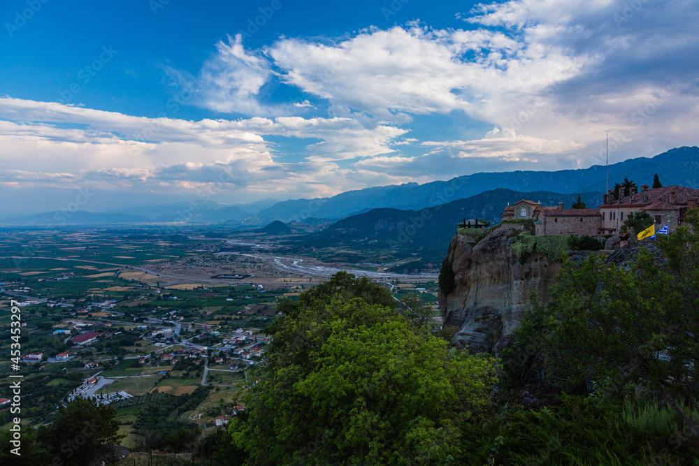 ギリシャ　メテオラの断崖絶壁の岩山の上に建つ聖ステファノス修道院と奇岩群の隙間から覗くカランバカの街並み