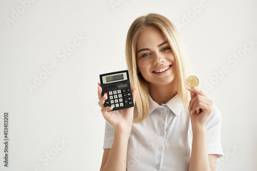 woman in white shirt calculator gold coin cryptocurrency