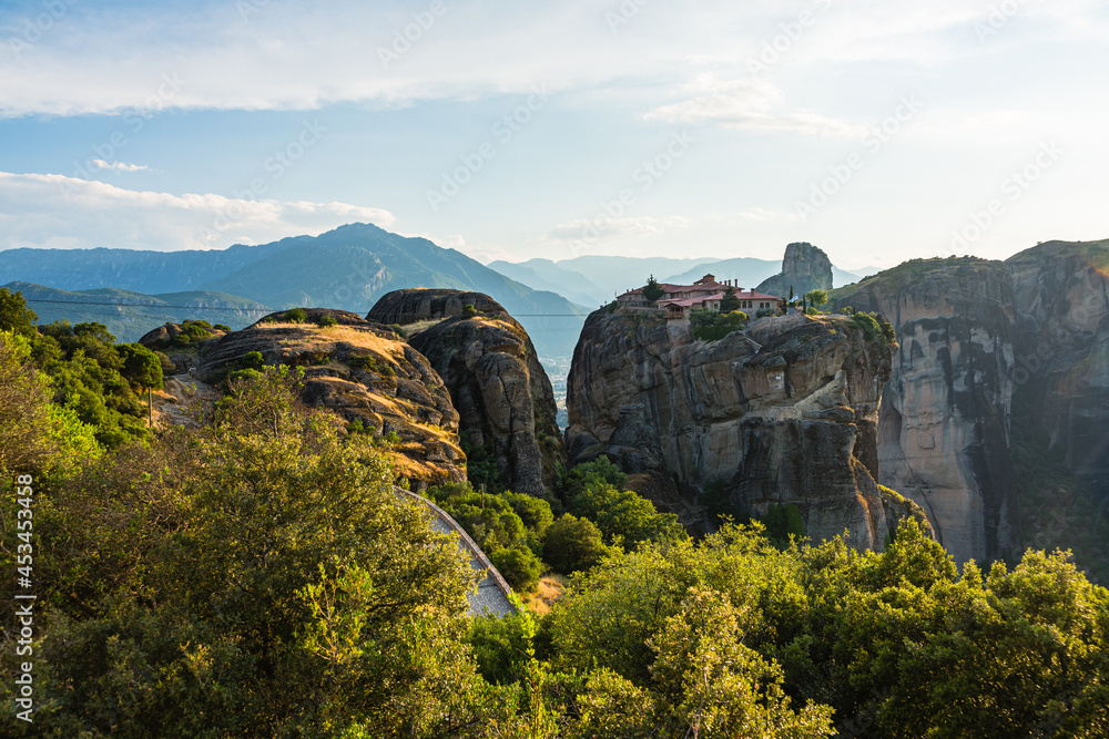 ギリシャ　メテオラの断崖絶壁の岩山の上に建つアギア・トリアダ修道院と奇岩群と後ろに広がるピンドス山脈