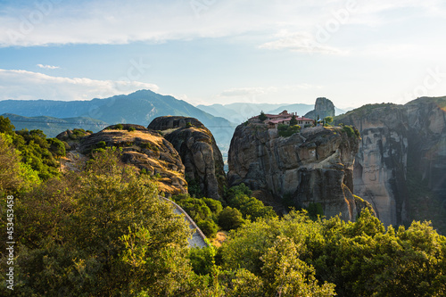 ギリシャ メテオラの断崖絶壁の岩山の上に建つアギア・トリアダ修道院と奇岩群と後ろに広がるピンドス山脈