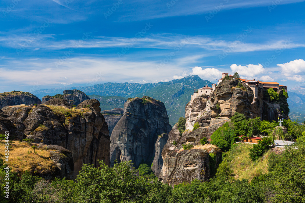 ギリシャ　メテオラの断崖絶壁の岩山の上に建つヴァルラアム修道院と奇岩群と後ろに見えるピンドス山脈