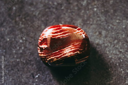 Pierre roulée polie jaspe rouge à bandes sur un fond noir - Minéral naturel photo