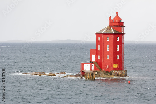 There is a deep red, octagonal lighthouse on a small archipelago in front of the municipality of Ørland, Norway photo