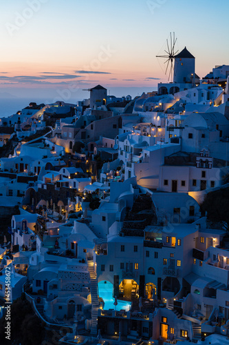 ギリシャ サントリーニ島のイアのイア・キャッスルから見えるの夕暮れのライトアップされた街並みと風車