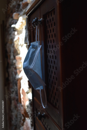 Mascarilla colgada de un mueble de madera antiguo