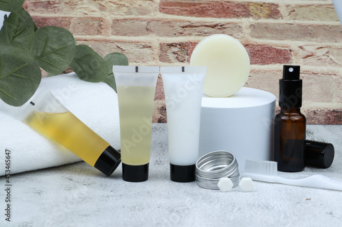 Set of bathroom amenities or hotel amenities - contained of shower gel, shampoo and conditioner, soap bar, toothbrush and toothpaste tablets with brick wall background