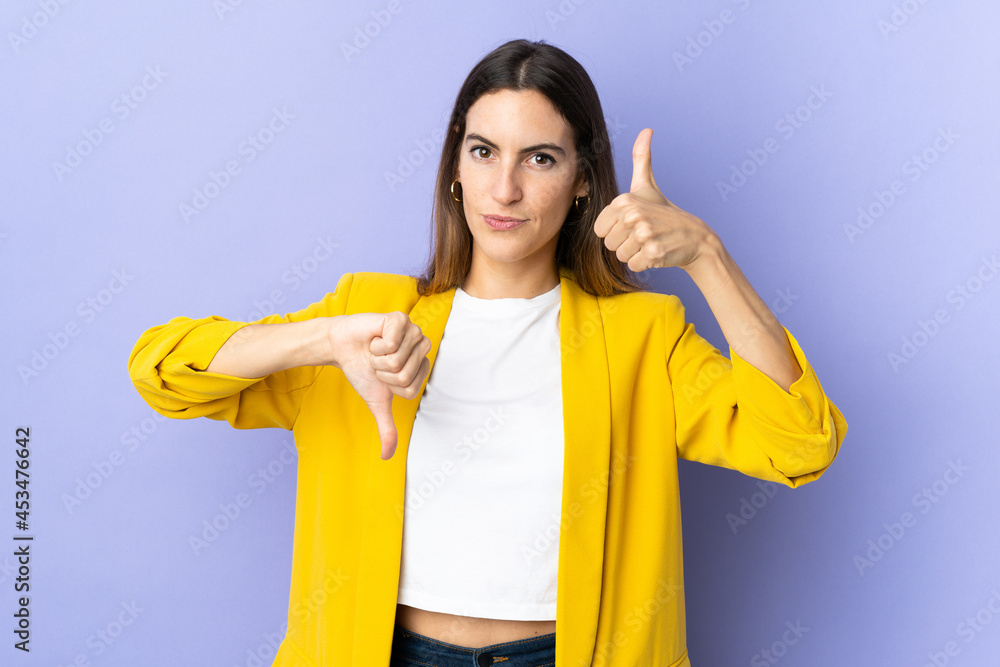Young caucasian woman over isolated background making good-bad sign. Undecided between yes or not Young caucasian woman over isolated background making good-bad sign. Undecided between yes or not