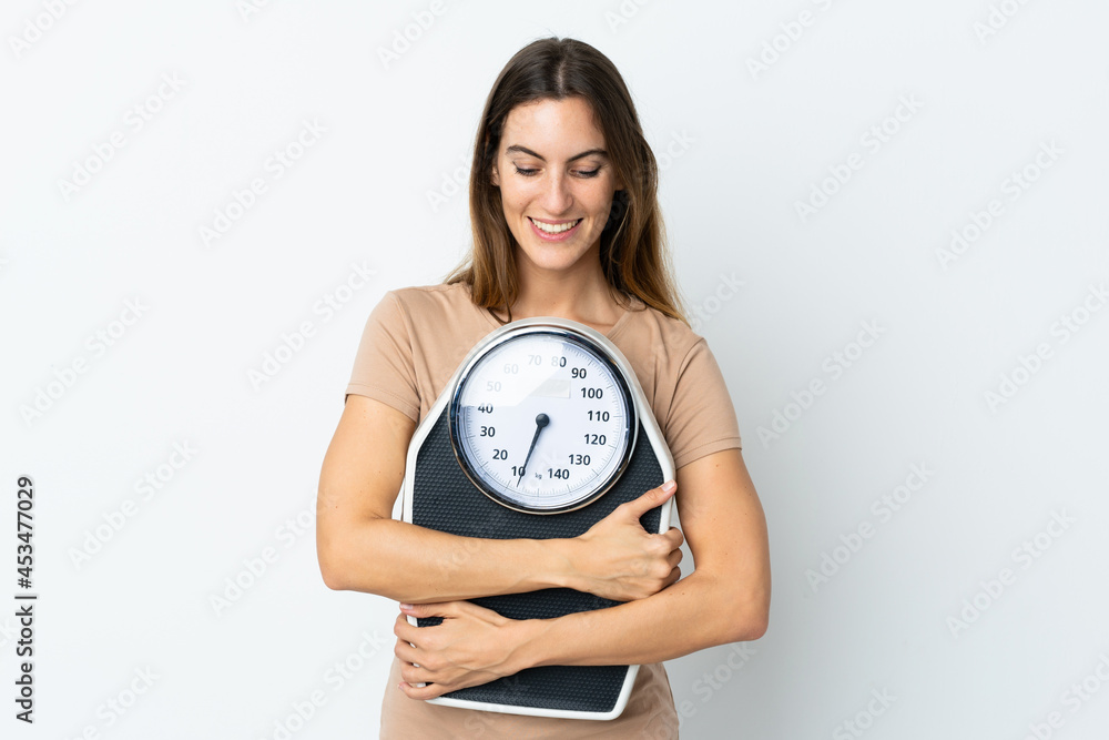 Young caucasian woman isolated on white background with weighing machine Young caucasian woman isolated on white background with weighing machine