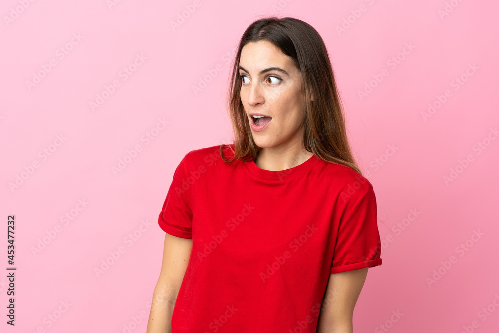 Young caucasian woman isolated on pink background doing surprise gesture while looking to the side Young caucasian woman isolated on pink background doing surprise gesture while looking to the side