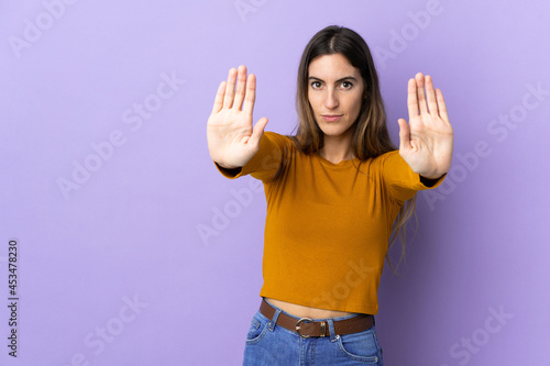 Young caucasian woman over isolated background making stop gesture and disappointed