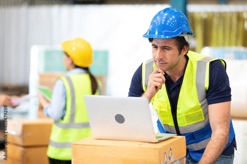 engineer or factory worker using laptop computer and thinking of something seriously in warehouse storage engineer or factory worker using laptop computer and thinking of something seriously in warehouse storage